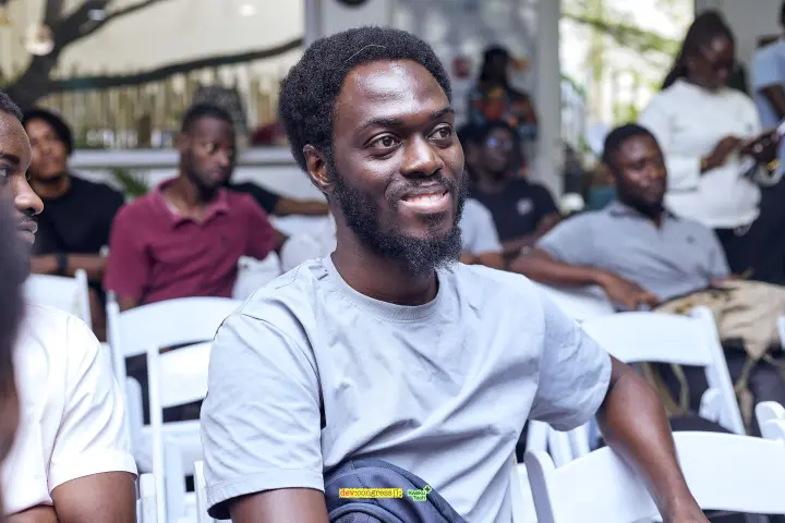 A smiling community member seated with the May meetup audience